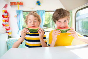 Boys eating watermelon in caravan, portrait