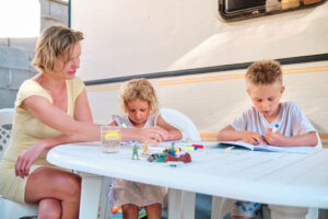 mother with children in her caravan at camping painting